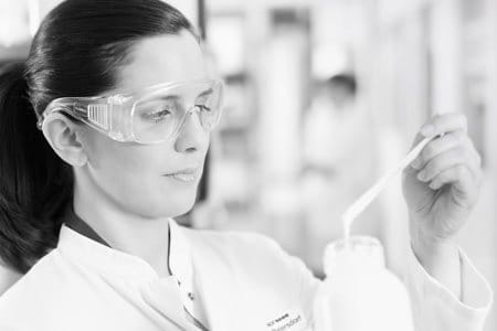 Female scientist with safety goggles testing a formula