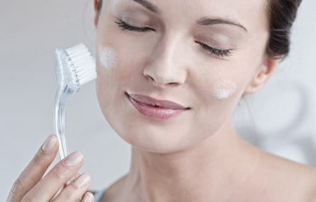 Woman cleaning her facial skin with brush