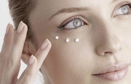 Woman applying cream under her eyes