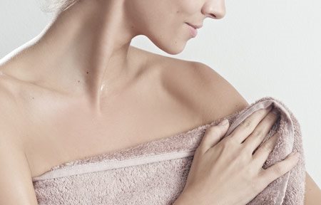 Woman pats her skin after showering