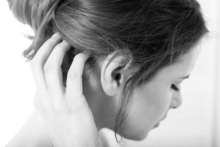 A woman in discomfort, touching her scalp